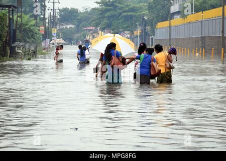 Colombo, Sri Lanka. 23rd May, 2018. People wade through water in suburban areas of Colombo, Sri Lanka, on May 23, 2018. The death toll from high winds and rains which lashed out across Sri Lanka since Saturday reached eight on Tuesday while over 38,000 people were affected, the Disaster Management Center said in its latest update. Credit: Gayan Sameera/Xinhua/Alamy Live News Stock Photo