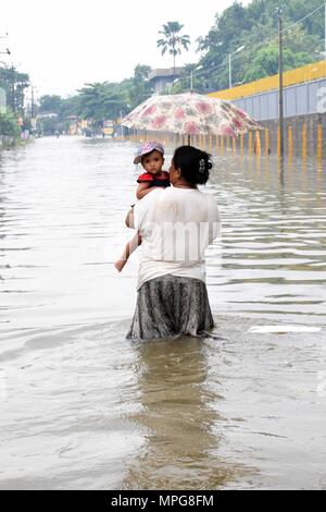 Colombo, Sri Lanka. 23rd May, 2018. A woman wades through water with a child in suburban areas of Colombo, Sri Lanka, on May 23, 2018. The death toll from high winds and rains which lashed out across Sri Lanka since Saturday reached eight on Tuesday while over 38,000 people were affected, the Disaster Management Center said in its latest update. Credit: Gayan Sameera/Xinhua/Alamy Live News Stock Photo