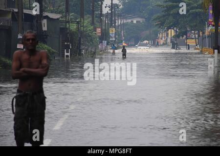 Colombo, Sri Lanka. 23rd May, 2018. People wade through water in suburban areas of Colombo, Sri Lanka, on May 23, 2018. The death toll from high winds and rains which lashed out across Sri Lanka since Saturday reached eight on Tuesday while over 38,000 people were affected, the Disaster Management Center said in its latest update. Credit: Gayan Sameera/Xinhua/Alamy Live News Stock Photo