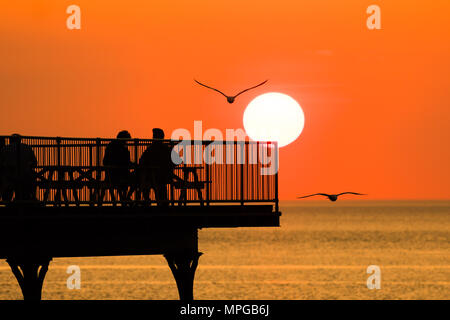 Aberystwyth  Wales UK, Wednesday  23 May 2018  UK Weather: People are silhouetted against the setting sun as they enjoy a a drink on a warm spring evening at the end of Aberystwyth’s truncated seaside pier.   photo © Keith Morris / Alamy Live News Stock Photo