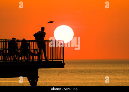 Aberystwyth  Wales UK, Wednesday  23 May 2018  UK Weather: People are silhouetted against the setting sun as they enjoy a a drink on a warm spring evening at the end of Aberystwyth’s truncated seaside pier.   photo © Keith Morris / Alamy Live News