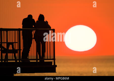 Aberystwyth  Wales UK, Wednesday  23 May 2018  UK Weather: People are silhouetted against the setting sun as they enjoy a a drink on a warm spring evening at the end of Aberystwyth’s truncated seaside pier.   photo © Keith Morris / Alamy Live News