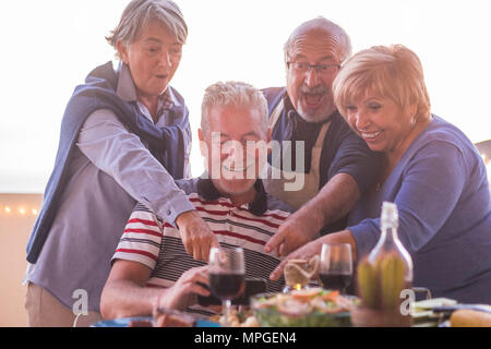 two beautiful couples doing picture with mobile phone during dinner on the rooftop patio outdoor in vacation. lifestyle for retired happy concept Stock Photo