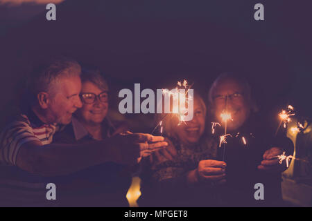 celebration time for party or new year eve for a group of senior friends with fire sparks. averybody together having  fun at night smiling and laughin Stock Photo