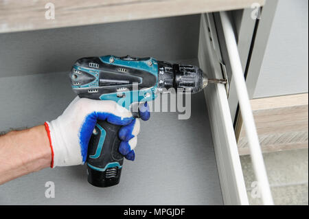 Installation of kitchen. Workman fixes the drawer in cabinet. Stock Photo