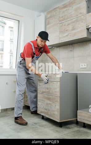 Installation of kitchen. Workman installs cabinet into place. Stock Photo