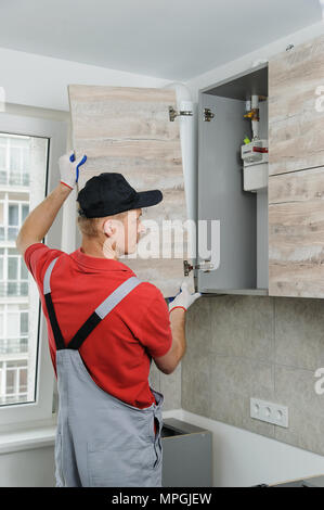 Installation of kitchen. Workman installs doors to kitchen cabinet. Stock Photo