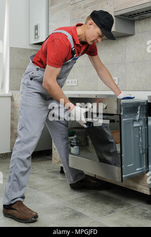 Installation of household appliances. Workman installing a built-in electric oven. Stock Photo