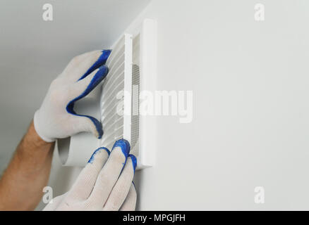 Worker installs ventilation grille on the wall. Stock Photo