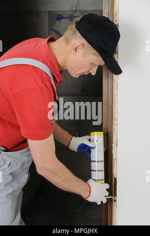 Installing door unit. Workman fixed the door frame using mounting foam. Stock Photo