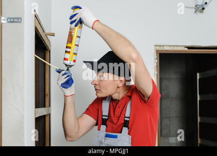 Installing door unit. Workman fixed the door frame using mounting foam. Stock Photo