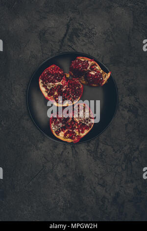 cut pomegranate on black plate Stock Photo