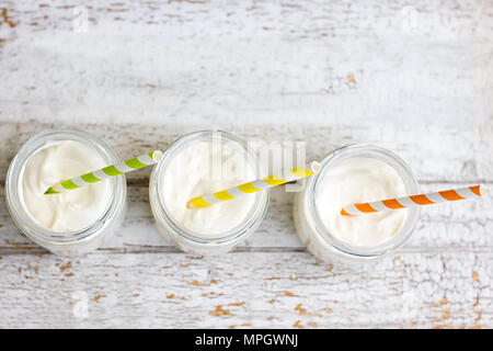 Yogurt in three small jars with straws. top view Stock Photo