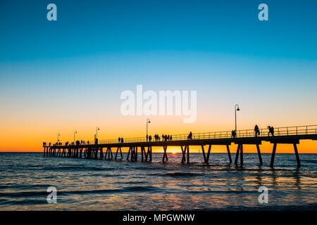 People walking along Glenelg Beach jetty at sunset, South Australia Stock Photo