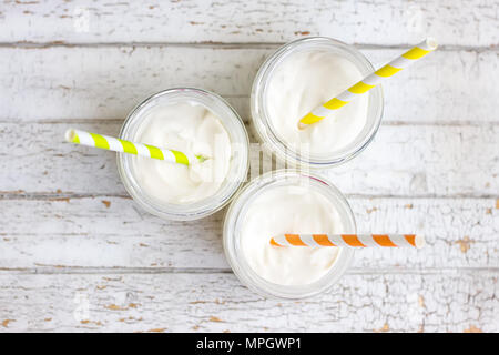 Yogurt in three small jars with straws. top view Stock Photo