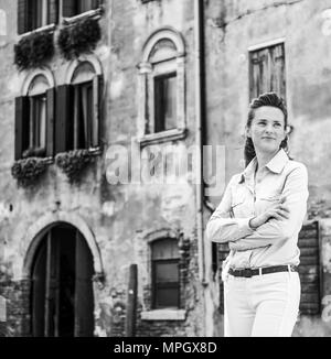 Relaxing, an elegant female tourist is standing with her arms crossed near a Venice canal. Everything in Venice is so enthralling... Stock Photo