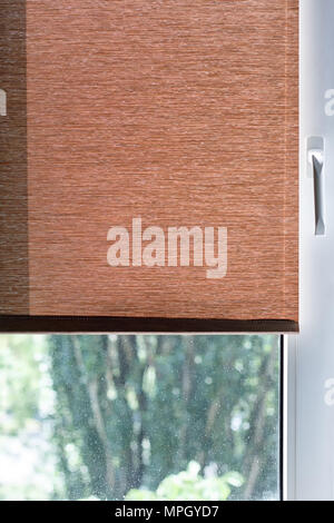 Brown fabric blinds on a white plastic window Stock Photo
