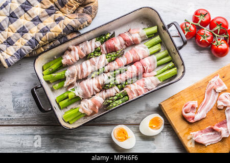 Tasty food bacon wrapped asparagus in frying pan. Stock Photo