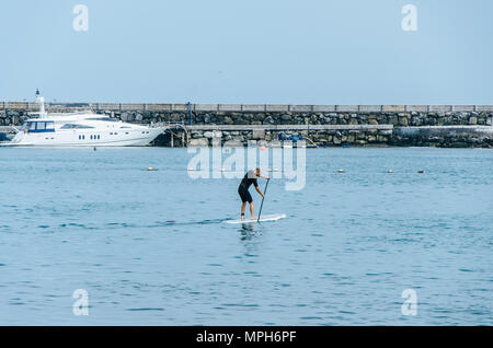 Stand up paddle board man paddleboarding on Peruvian beach standing happy on paddleboard on blue water. Stock Photo