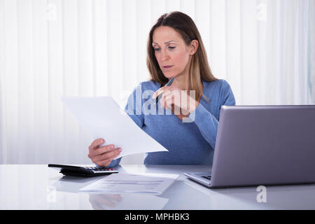 Elevated View Of Woman Calculating Invoice With Calculator At Home Stock Photo