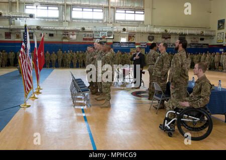 The official party of the Troops First Foundation’s Operation Proper Exit pay tribute to the American flag during the playing of the national anthem in the Area Support Group - Kuwait Morale Warfare Recreation gym before participating in a Hero’s Town Hall in Camp Arifjan, Kuwait, on Mar. 14, 2017. (U.S. Army photo by Staff Sgt. Dalton Smith) Stock Photo