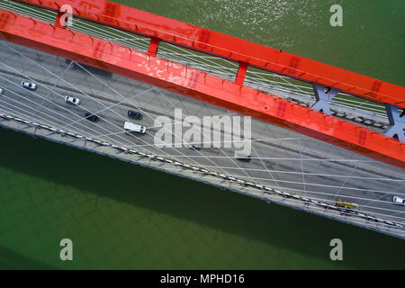 Helicopter drone shot. Aerial photography of the modern orange big bridge across the river in a megacity,green river Stock Photo
