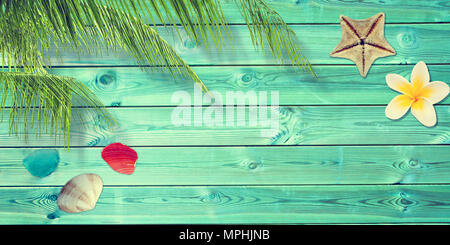 Beach and summer background with blue planks, palm tree branch and seashells Stock Photo