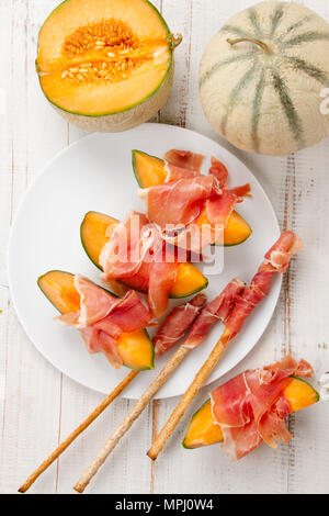 Cantaloupe melon with ham, a traditional Spanish and Italian appetizer served with wholemeal grissini Stock Photo