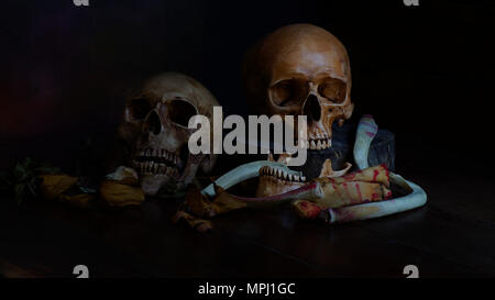pile of two human skull and skeleton wit dry rose flower on old wood background,concept in died because of love Stock Photo
