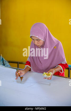 Krabi, Thailand - May 2, 2015: Muslim woman drawing on pattern line on Batik fabric by liquid candle inn her home in Krabi, Thailand Stock Photo