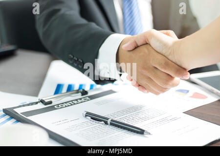 Two businessmen shaking hand after successful negotiate and signing on contract about working and partner together on working table in office. Stock Photo