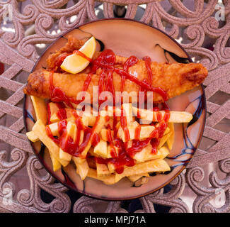 fish and chips meal with a lemon wedge or wedge of lemon on an outdoor table. Stock Photo