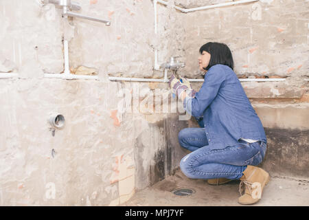 Clever woman repairing her bathroom sink pipe with  positive attitude. using a work tool. Selective focus and small depth of field Stock Photo