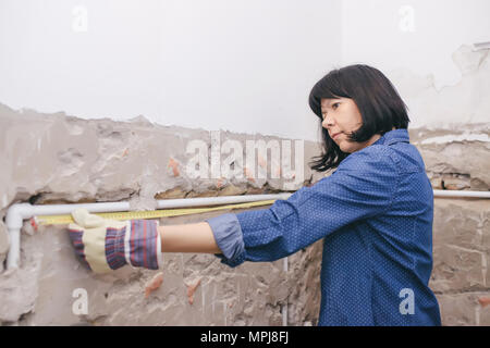 Clever woman repairing her bathroom sink pipe with  positive attitude. Using measuring tape ruler. Stock Photo