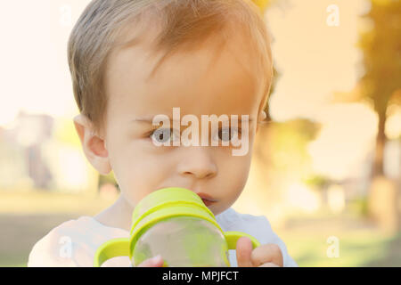 Cute Baby Boy Drinking Milk Bottle in a park Stock Photo