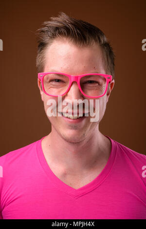 Young handsome man wearing pink shirt and eyeglasses against bro Stock Photo