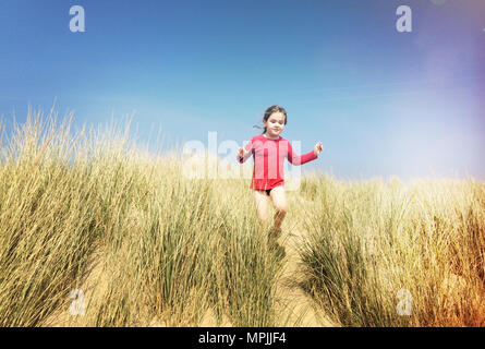 Young girl having fun running amid the sand dunes at the seaside, age 6 to 9 years, May 2009 --- Image by © Paul Cunningham Stock Photo