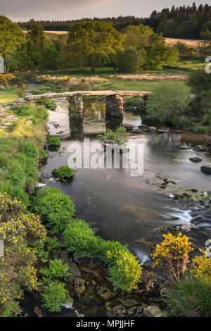 On a warm summer evening, after the tourists depart, the East Dart River trickles beneath the beautiful granite built Clapper Bridge at Postbridge in  Stock Photo
