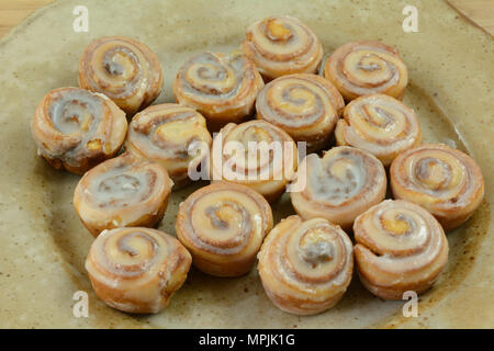Close up of small cinnamon rolls with icing on ceramic bunch or breakfast party platter Stock Photo