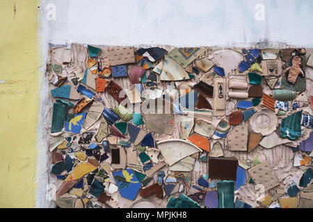 Broken plates, broken dishes, old tiles on the wall, on the left there is a strip of yellow plaster, on top is a white strip, an empty space for text. Stock Photo