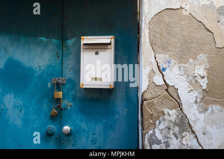 White vintage mailbox on a blue metal door old house with priknaki destruction. Stock Photo
