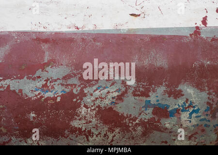 Abstract grunge background maroon stone wall with crumbling plaster, top white blank stripe for text. Stock Photo