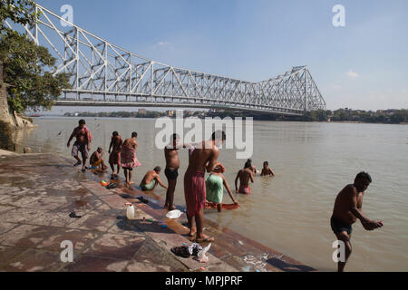 India, West Bengal, Kolkata, Men wash and bathe in the Hooghly River with Howrah Bridge in the background. Stock Photo