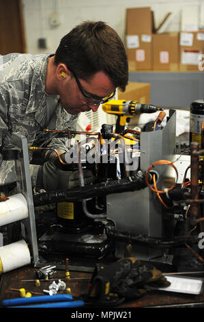 At Minot Air Force Base, North Dakota, Senior Airmen from the 5th Civil Engineer Squadron install a compressor unit on February 28, 2017, as part of HVACR operations. Technicians are responsible for installing, maintaining, and repairing heating, ventilation, air conditioning, and refrigeration systems, including furnaces, boilers, stoves, heat exchangers, blowers, fans, and radiant heaters. Work ensures climate control, operational readiness, and support for Air Force personnel and base infrastructure. Stock Photo