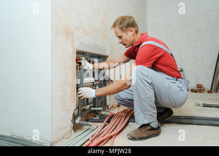 Installation of home heating. A worker attaches the tube to the collector heating. Stock Photo