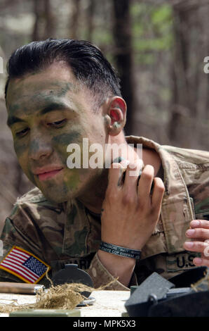 A Soldier applies camouflage face paint and adjusts equipment during Expert  Infantryman Badge (EIB) training at Fort Jackson. The exercise teaches  infantrymen to apply camouflage principles to personal gear, uniforms, and  exposed