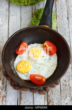 Scrambled eggs in an iron pan on the rustic wooden table Stock Photo