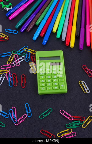 calculator, paper clips, markers on black Board. School and business concept Stock Photo