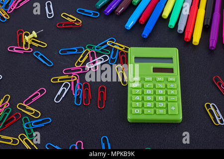 calculator, paper clips, markers on black Board. School and business concept Stock Photo
