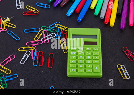 calculator, paper clips, markers on black Board. School and business concept Stock Photo